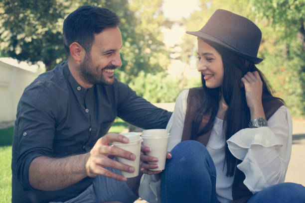istock Happy young couple sitting in the park drinking coffee 850875536