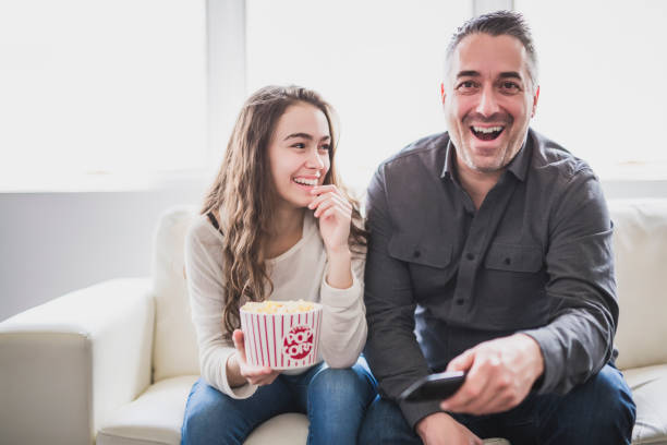 Portrait of a young man and daughter watching TV while eating popcorn on the sofa Portrait of a young man and daughter watching TV while eating popcorn on the sofa 2000 photos stock pictures, royalty-free photos & images