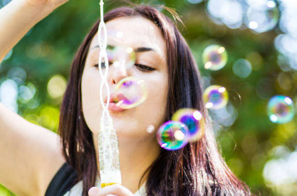 istock young woman blowing soap bubbles in the park 850889008