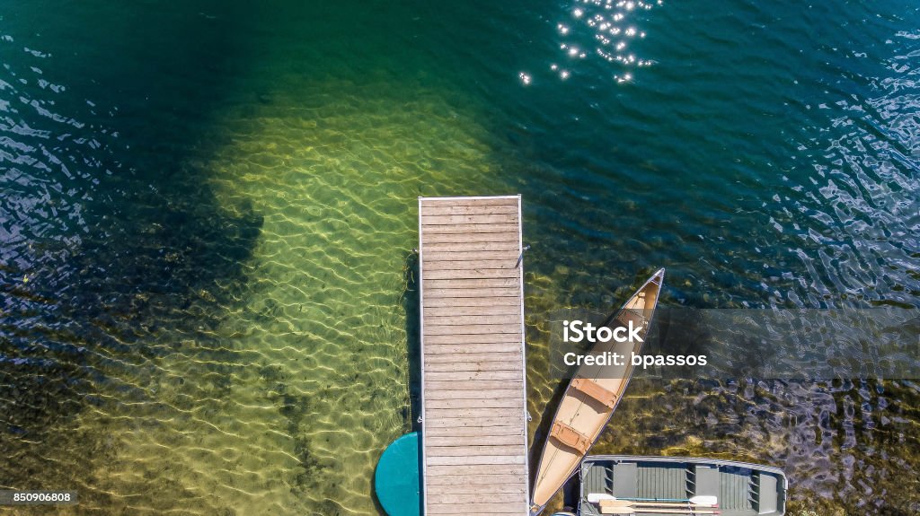 Lake dock seen from above Lake dock with canoe on a clear water lake Aerial View Stock Photo