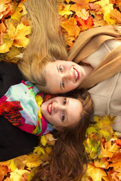 istock two girls lie on a leaf in an autumn park 850910542