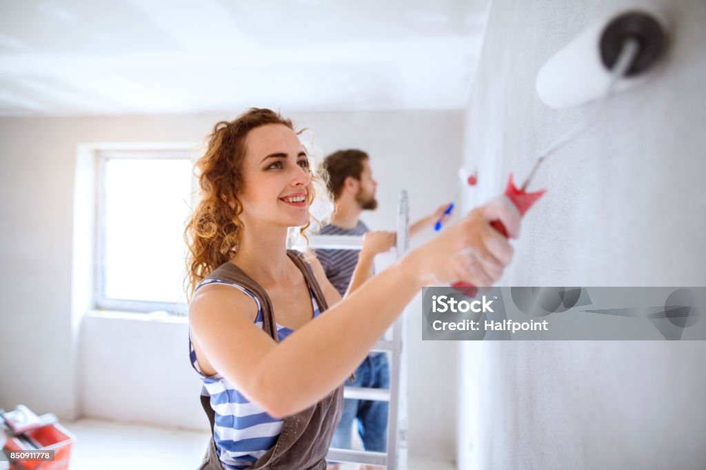 Jeune couple murs peinture dans leur nouvelle maison. - Photo de Peindre libre de droits