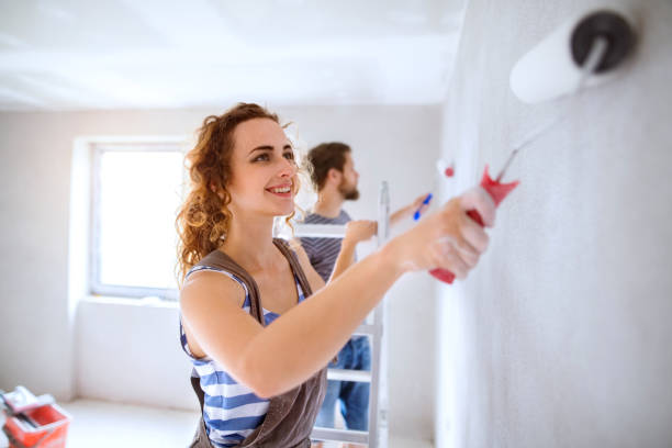 Young couple painting walls in their new house. Beautiful young couple having fun and painting walls using paint rollers in their new house. Home makeover and renovation concept. wall renovation stock pictures, royalty-free photos & images