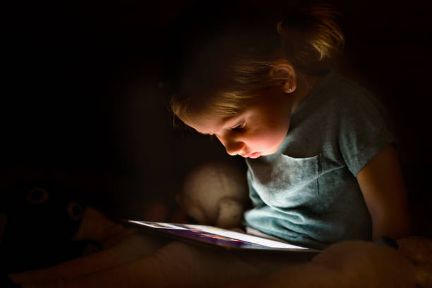 istock Little girl at home at night watching something on tablet. 850923794