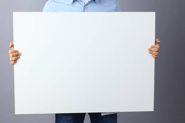 istock Businessman holding a blank board, standing on gray background 850931568