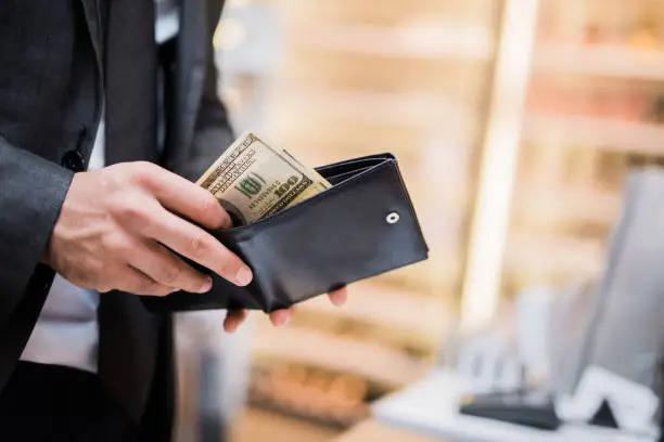 Photo of Young businessman taking money out of his wallet