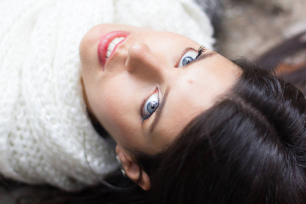 Beautiful young woman with blue eyes looking at camera sitting on urban bench. Girl ith sweet look sitting on park.