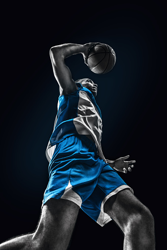 The african man basketball player jumping with ball on black background