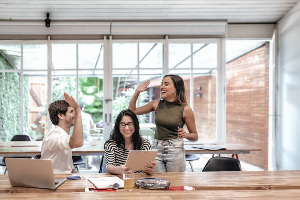 three happy young brazilian business people in office - cheering business three people teamwork imagens e fotografias de stock