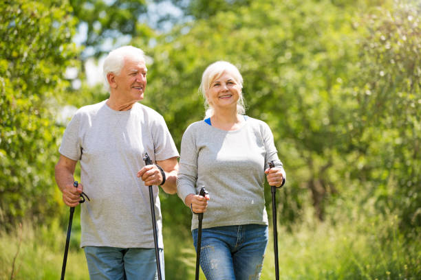 Senior couple nordic walking in park Senior couple nordic walking in park nordic walking pole stock pictures, royalty-free photos & images