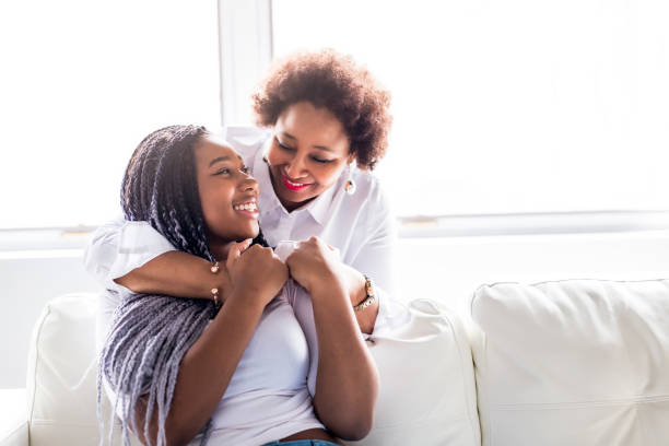 affectionate mother and daughter sitting on sofa