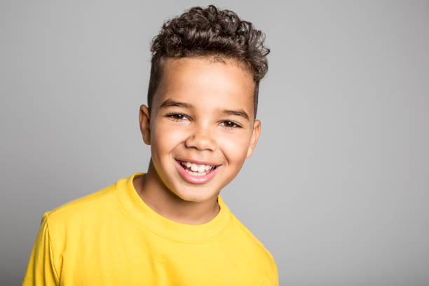 adorabile ragazzo africano su sfondo grigio studio - 8 9 anni foto e immagini stock