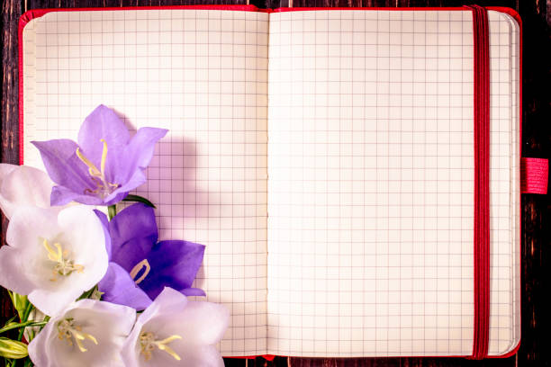 blank note book with spring flowers on wooden background. Top view with copy space. Holiday mockup.