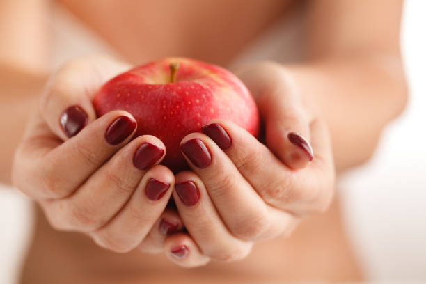 istock The big red apple in beautiful female hands 850997038