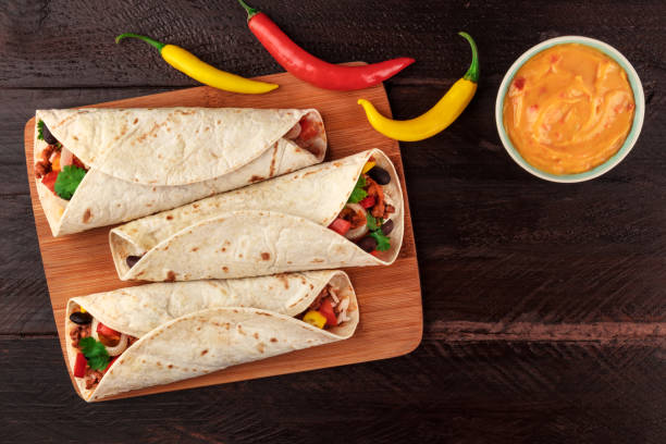 istock Mexican burritos with cheese salsa, chili peppers, and copyspace 851003344