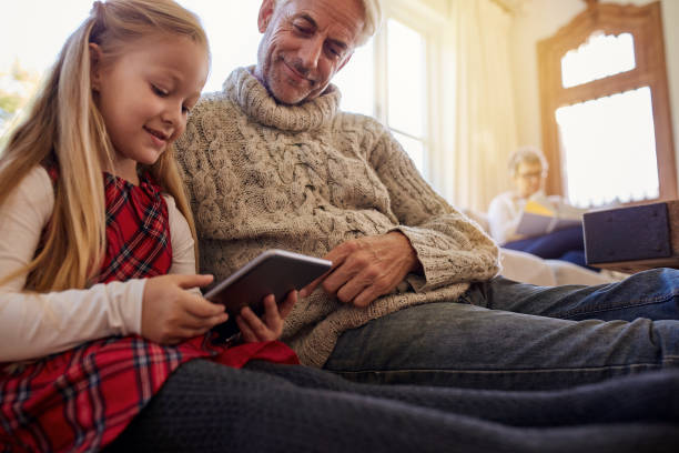 istock Little girl with grandfather using tablet pc at home 851004552