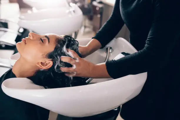 Photo of Woman getting hair shampooed at salon