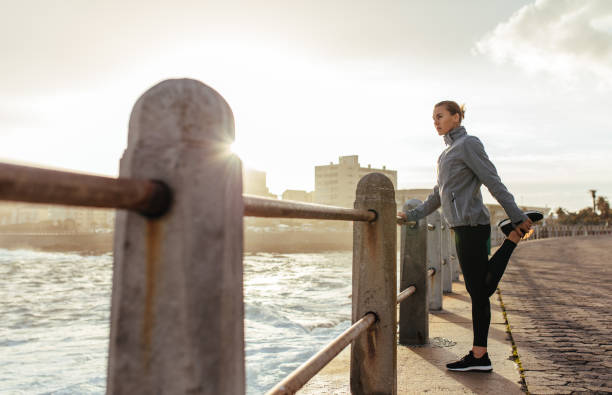 coureur de femme faisant s’étendant à la promenade de bord de mer - railing beautiful human leg people photos et images de collection