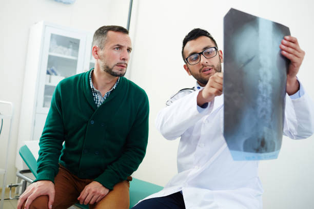 Visiting radiologist Radiologist with x-ray results explaining his patient problem with spinal cord x ray results stock pictures, royalty-free photos & images
