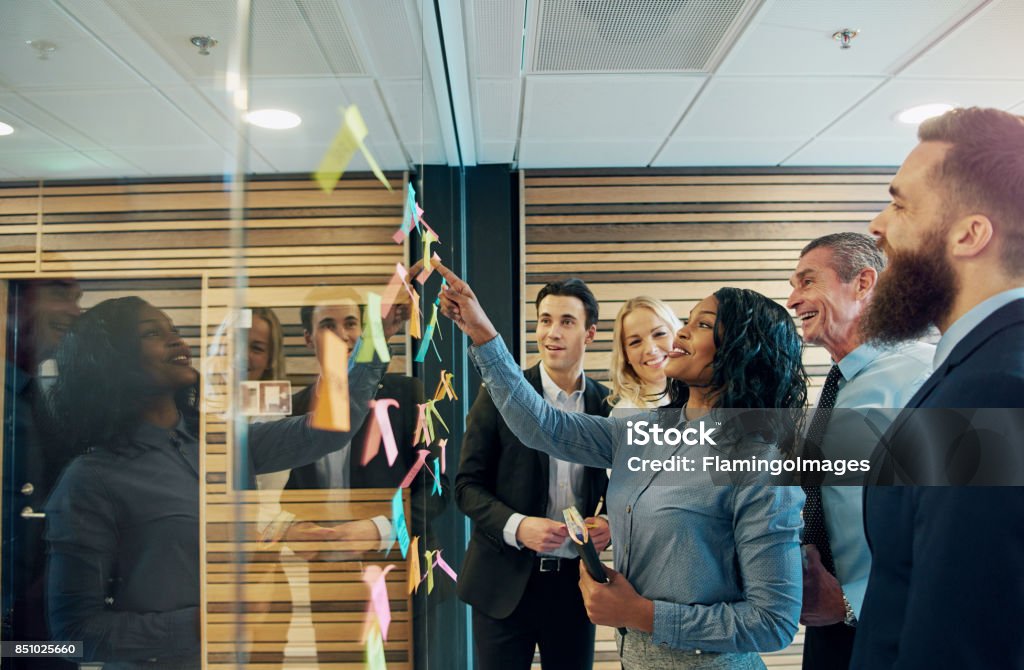 Cheerful entrepreneur team talking in the office Smiling multiethnic staff at the wall with stickers on a meeting in the company. Leadership Stock Photo