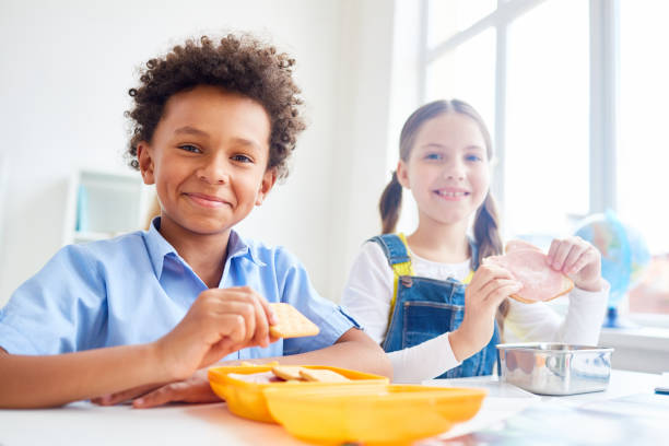 Dining at break Modern schoolkids eating snacks from containers at break school lunch child food lunch stock pictures, royalty-free photos & images