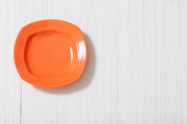istock orange plate on white wooden background 851033984