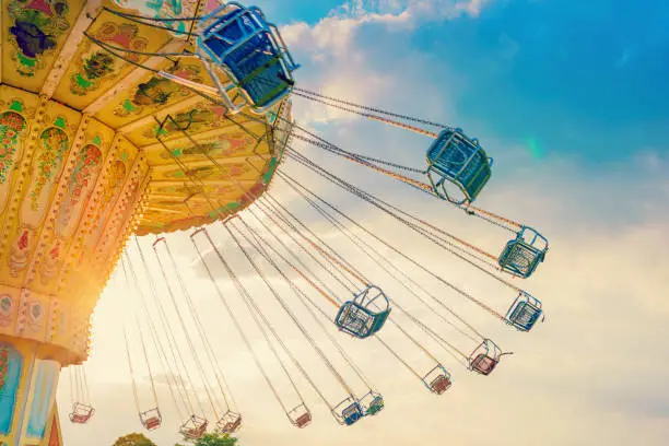 Photo of carousel ride spins fast in the air at sunset - a swinging carousel fair ride at dusk