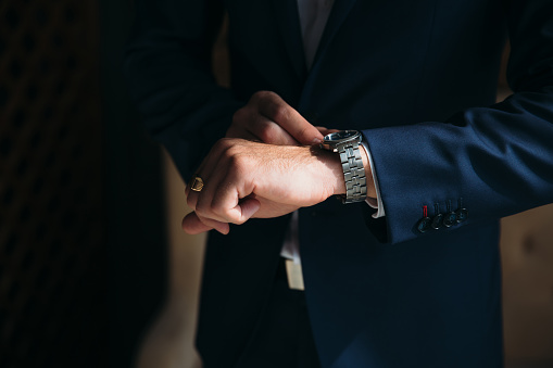 Man in blue jacket with boutonniere wear wrist watches. Concept of jewelry, dress.