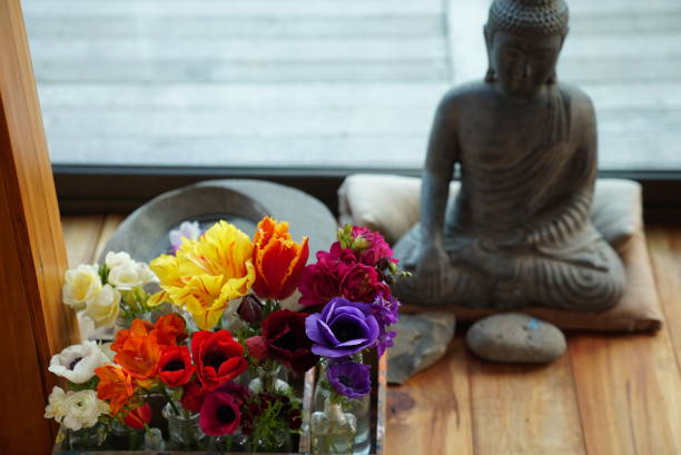 Preparing the decoration for a yoga session with a buddha sculpture, a candle and flowers.