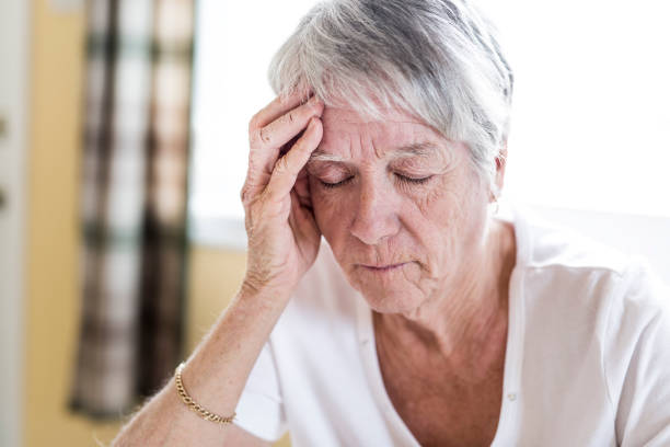 istock Mature woman at home touching her head with her hands while having a headache pain 851106754