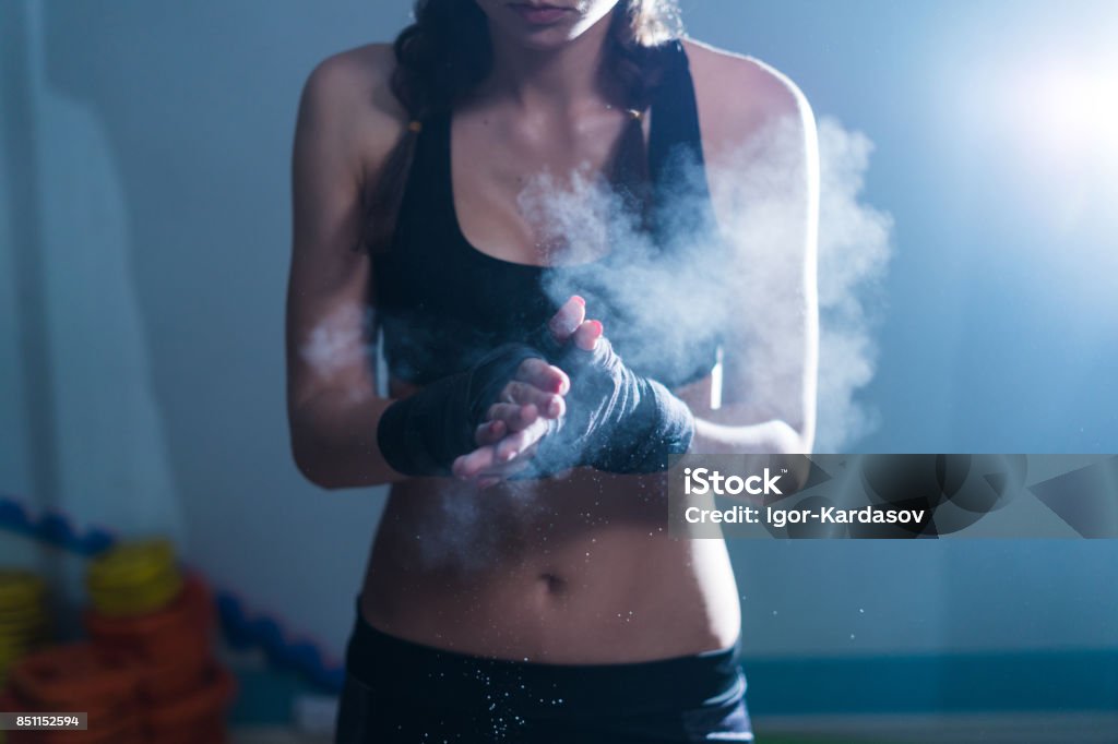 Young fighter boxer girl in training with heavy punching bag Young fighter boxer fit girl wearing hand bandage preparing before training. She has magnesia in hands Girl Power Stock Photo