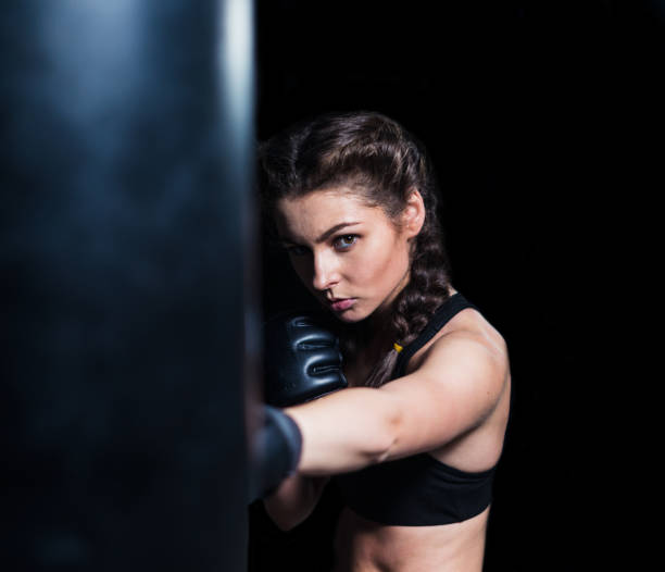 istock Young fighter boxer girl in training with heavy punching bag 851158446