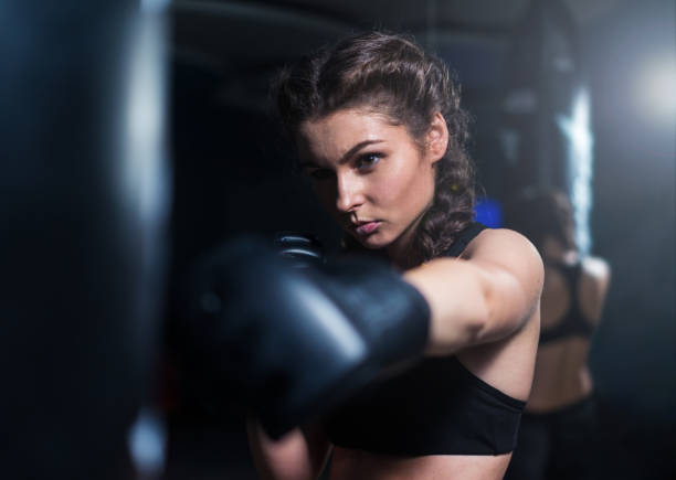 istock Young fighter boxer girl in training with heavy punching bag 851158712