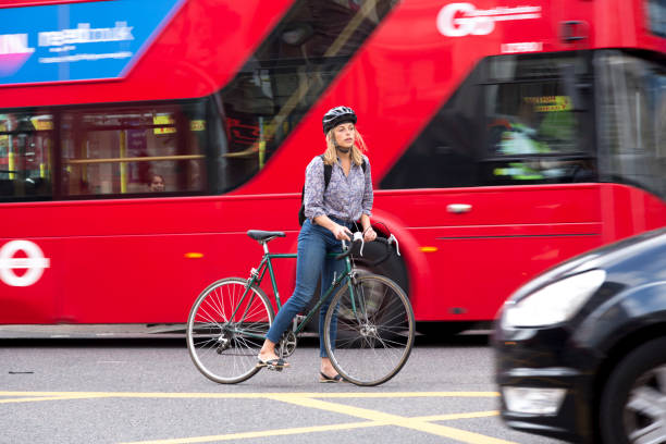 London, UK - August 19, 2017: A young woman on a bicycle waits on a junction to take a turn. London traffic is a threat for bicycle users