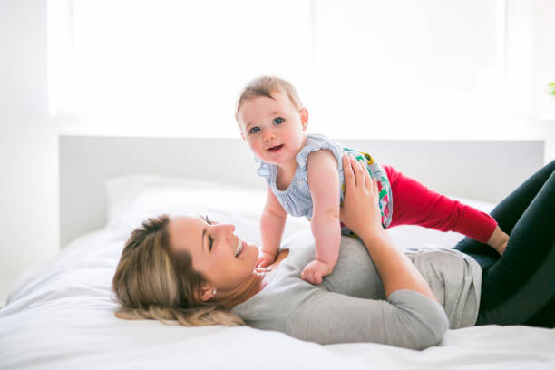 istock Pretty baby sit on mom in silk bed 851169852