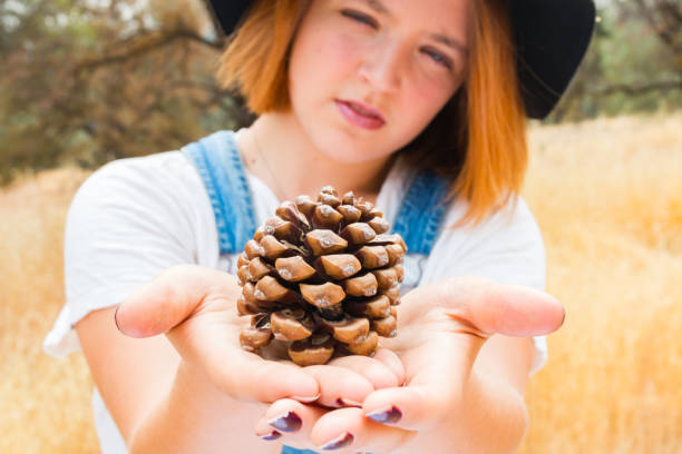 istock Young Girl in Overalls Holding up a Pinecone 851173670