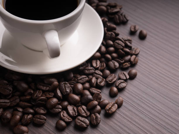 Black coffee cup on brown wood table with coffee bean stock photo