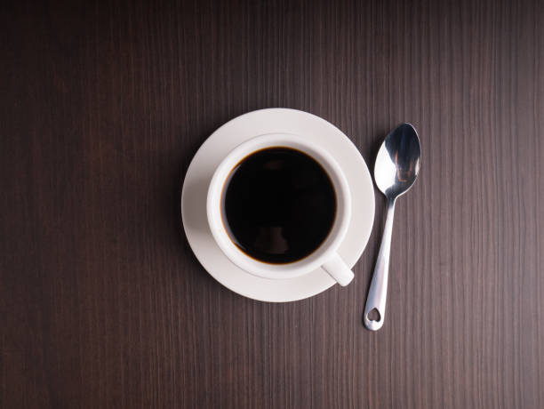 Black coffee cup on brown wood table with coffee bean stock photo