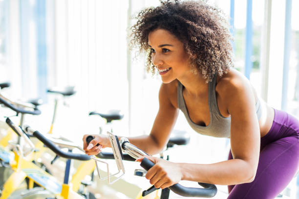 ジムでエアロバイクに心臓の演習を行う女性 - spinning gym exercising cycling ストックフォトと画像
