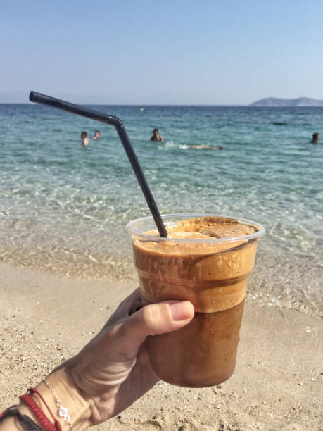 istock hand holding a frappe against sea in Greece 851176824