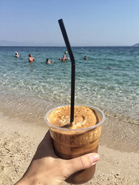 istock hand holding a frappe against sea in Greece 851176876