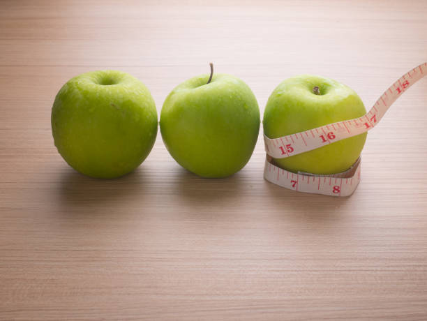 Apples with tape measure on blue wood background, lose weight concept stock photo