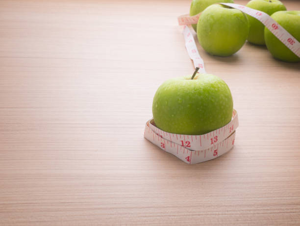 Apples with tape measure on blue wood background, lose weight concept stock photo