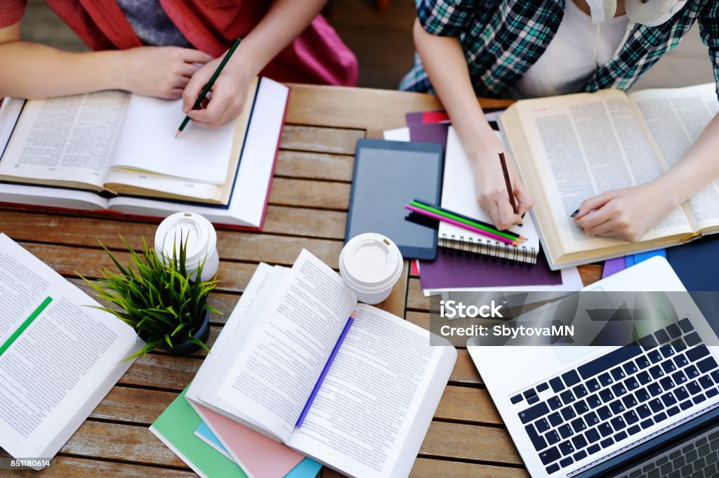 Top view of young students with books and notes in cafe Young couple with books and notes in cafe. Smart young guy and girl in University campus. Learning and education for young people. Top view of students studying or doing homework Studying Stock Photo