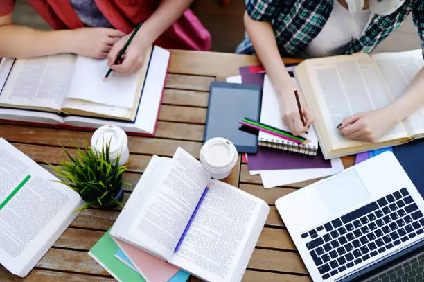 Photo of Top view of young students with books and notes in cafe