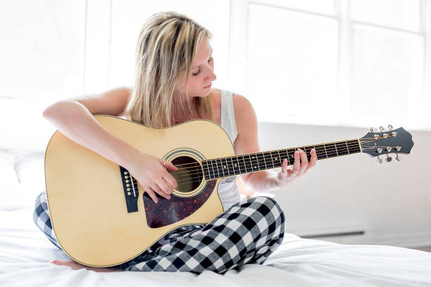 istock Smiling woman with guitar sitting on the bed 851183262