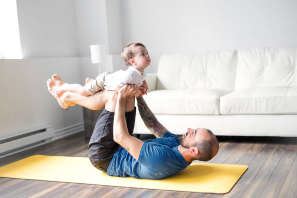 uomo sportivo è impegnato in fitness e yoga con un bambino a casa - child exercising little boys toddler foto e immagini stock