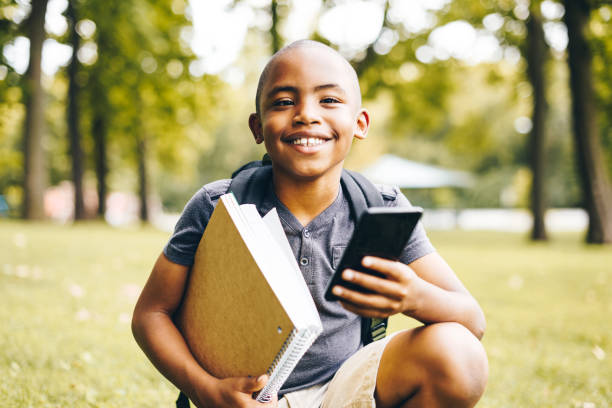 niño listo para usar el teléfono de la escuela - outdoors book reading accessibility fotografías e imágenes de stock
