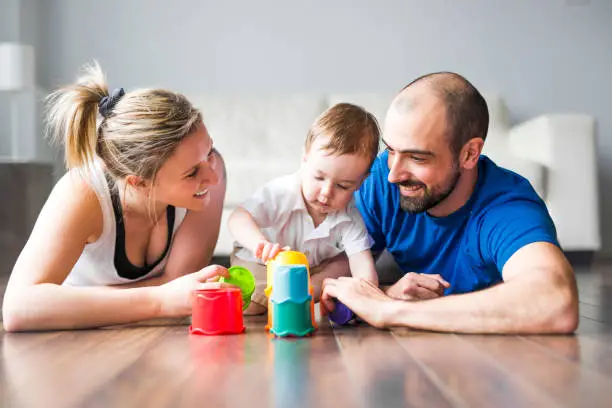 Photo of Happy family with parents and son playing with colorful blocks in the livingroom