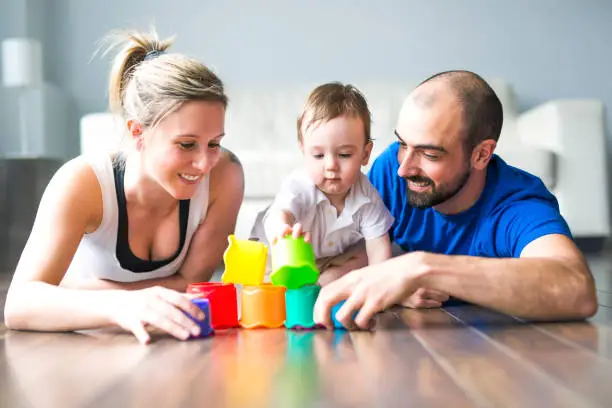 Photo of Happy family with parents and son playing with colorful blocks in the livingroom